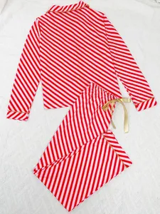 Macro view of red and pink diagonal striped Christmas pajama set with gold piping detail