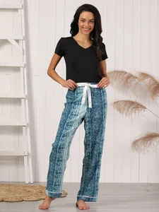 Female model wearing black V-neck t-shirt and blue snake print pajama pants in a studio setting.