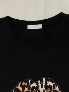 Detailopname van zwart pyjama-topje met ronde hals, luipaardprint en maat S label.