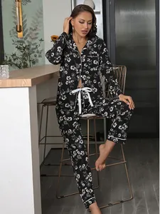 Full lifestyle view of a model in a black floral long-sleeve pajama set at home