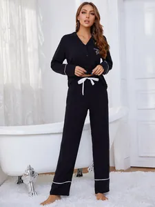 Modelo con conjunto de pijama negro de manga larga con ribetes blancos en una escena de baño chic