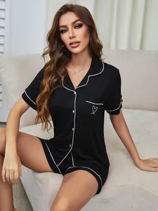 Nahaufnahme des schwarzen Modal-Pyjama-Sets mit weißer Paspelierung und Herz-Detail