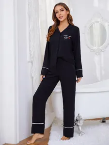 Vista detallada del conjunto de pijama negro con bordado Kiss y ribetes blancos.