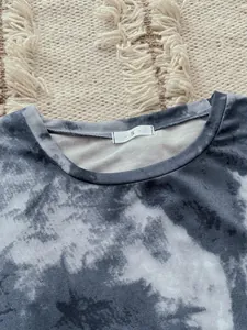 Close-up view of the crew neck on a gray tie-dye pajama top with a size S label