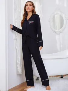 Vista completa del conjunto de pijama negro con cuello de solapa y ribete blanco.