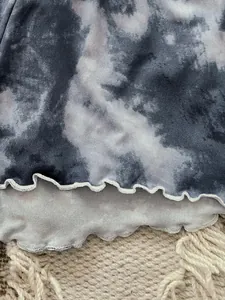 Macro view of the decorative lettuce edge hem on soft grey tie-dye pajama set fabric detail
