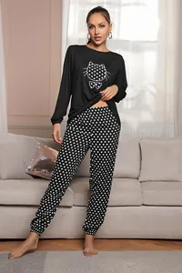 Dettaglio del pigiama nero da donna con stampa a gatto e pantaloni a pois coordinati, set