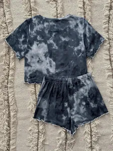 Detail view of a grey and black tie-dye two-piece pajama set on a textured rug.