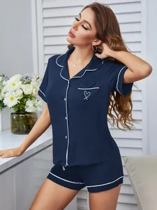 Detailansicht des marineblauen Pyjama-Sets mit weißen Paspeln und Herzstickerei