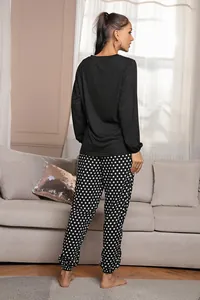 Vista posteriore di un comodo pigiama da donna con top nero e pantaloni a pois bianchi