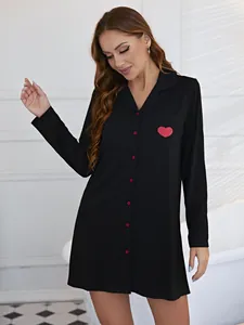 Gros plan d'une nuisette noire à manches longues avec imprimé cœur rouge sur poche.