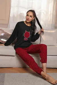 Modella indossa un top del pigiama nero con gatto a scacchi e pantaloni a quadri rossi coordinati
