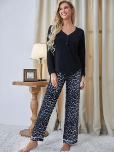 Donna in pigiama nero a maniche lunghe e pantaloni leopardati in ambiente domestico