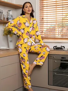 Model wearing a vibrant yellow floral loungewear set with long sleeves and pants in a cozy kitchen