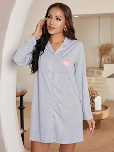 Détail d'une chemise de nuit grise à manches longues avec cœur rose imprimé sur poche.