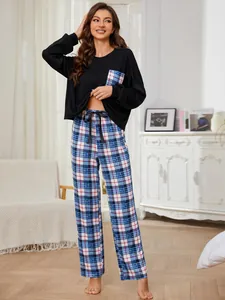 Stylish women's two-piece pajama set featuring black top and plaid pants in a home setting