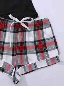 Detailweergave van een pyjamaset met rood geruite shorts en een wit satijnen strikje.