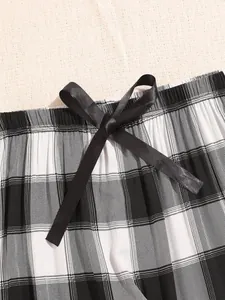 Close-up detail of the elastic waistband with a black satin bow on plaid loungewear pants