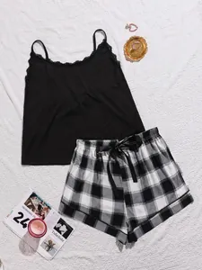 Detail van luxe dames pyjamaset met zwart kanten hemdje en geruite short op wit