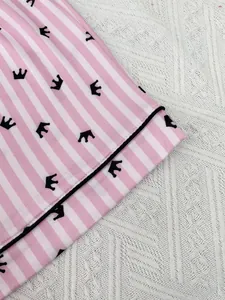Détail du tissu de pyjama pour femme à rayures roses et blanches avec motif de couronne noire