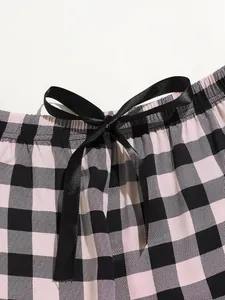 Close-up of pink and black checkered pajama pants with a black satin bow drawstring.