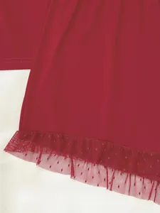 Gros plan de l'ourlet de pyjama rouge avec dentelle délicate et maille à pois finie.