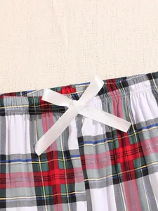 Close-up detail of women's plaid pajama pants featuring a white decorative satin bow tie