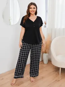 Full length view of a comfortable plus size pajama set featuring a black top and plaid trousers