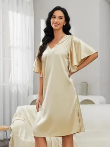 Full-length view of woman wearing champagne silk nightgown standing in cozy living room