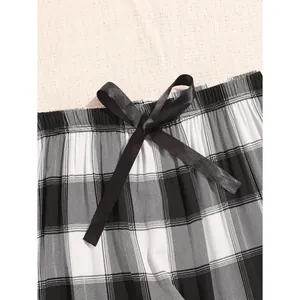 Black and white plaid pajama pants featuring a black satin bow at the waistband