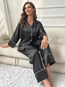 Elegant black satin pajama set with white piping detail shown in a cozy home setting
