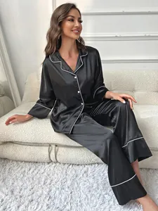 Elegant black satin pajama set for women featuring white contrast piping and classic lapel.