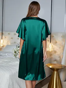Back view of a luxury emerald green satin nightgown in a cozy bedroom setting