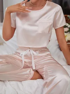 Close-up of elegant pink satin pajama set featuring a cropped top and comfy jogger pants