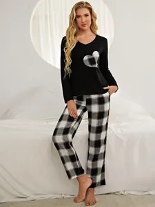 Women's pajama set featuring black top with plaid heart patch and matching pants