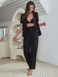 Model trägt ein schwarzes dreiteiliges Pyjama-Set mit BH-Top und langer Hose