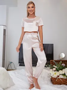 Elegant two-piece pink satin pajamas set featuring a short sleeve crop top and jogger pants