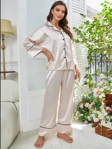 Full-length view of a woman in a pink satin two-piece pajama set with black piping
