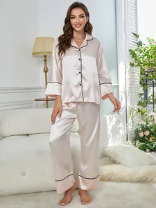 Elegant champagne silk pajama set with black piping worn by model in a cozy home setting
