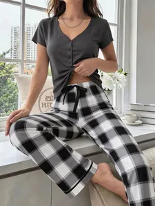 Detailed view of women's two-piece pajama set featuring grey v-neck top and plaid pants