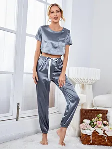 Detailed view of a two-piece satin pajama set with short-sleeved crop top and jogger pants