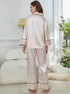 Back view of champagne satin pajama set with black piping in a cozy home setting