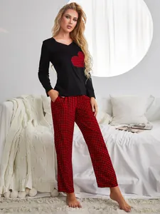 Detail view of women's black top with red buffalo check heart patch and matching pants