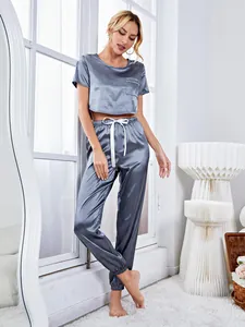 Full view of model wearing a two-piece grey satin pajama set with crop top and pants