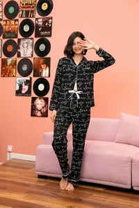 Lifestyle detail van zwarte pyjamaset met lange mouwen en wit cursief patroon en strik