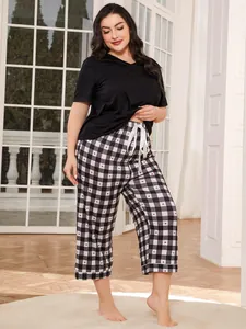 View of the plus size sleepwear set detailing the contrast of black top and plaid pants