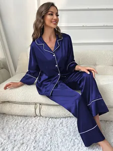 Elegant women's navy blue ice silk satin pajama set displayed on a stylish white sofa.