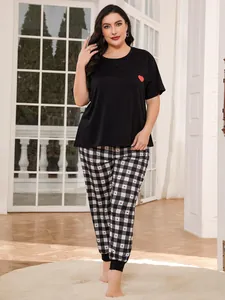 Full-body view of a plus-size woman wearing a black heart top and checkered pajama pants