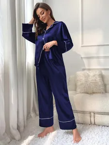 Women's navy blue satin pajama set featuring long sleeves and pants with white piping