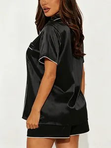 Side view of black satin short sleeve pajama set featuring elegant white piping